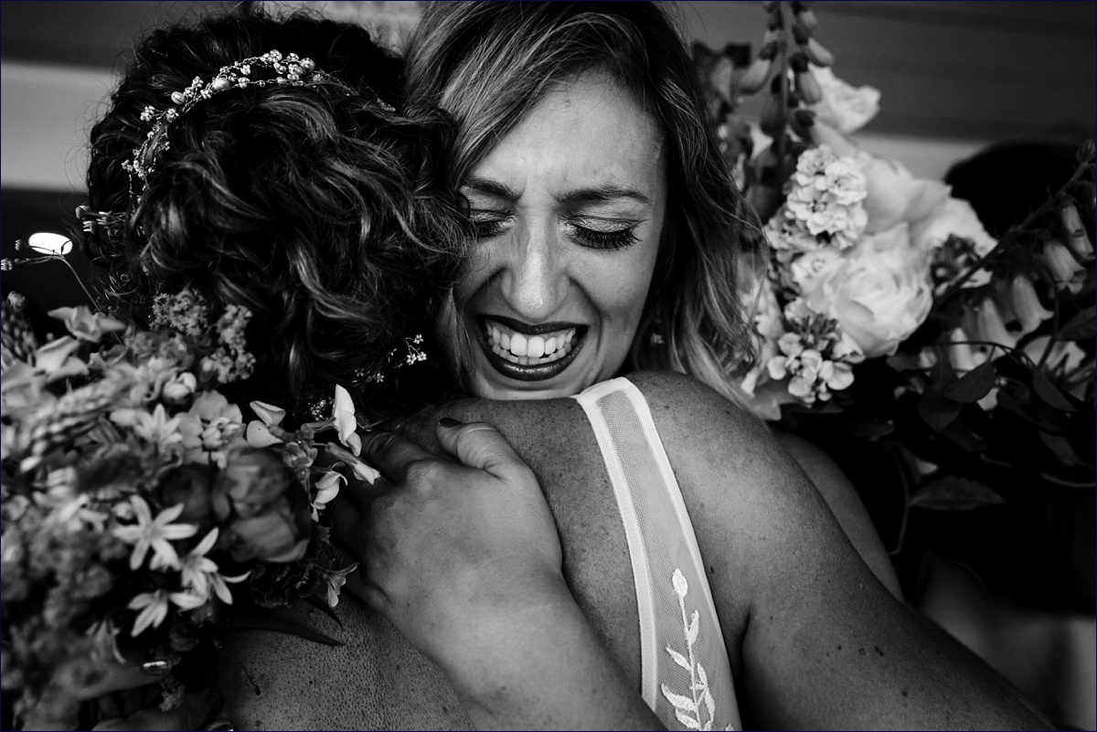 Linekin Bay Resort Wedding Photographer in Boothbay Maine a teary bridesmaid hugs onto the bride tightly after the ceremony is complete