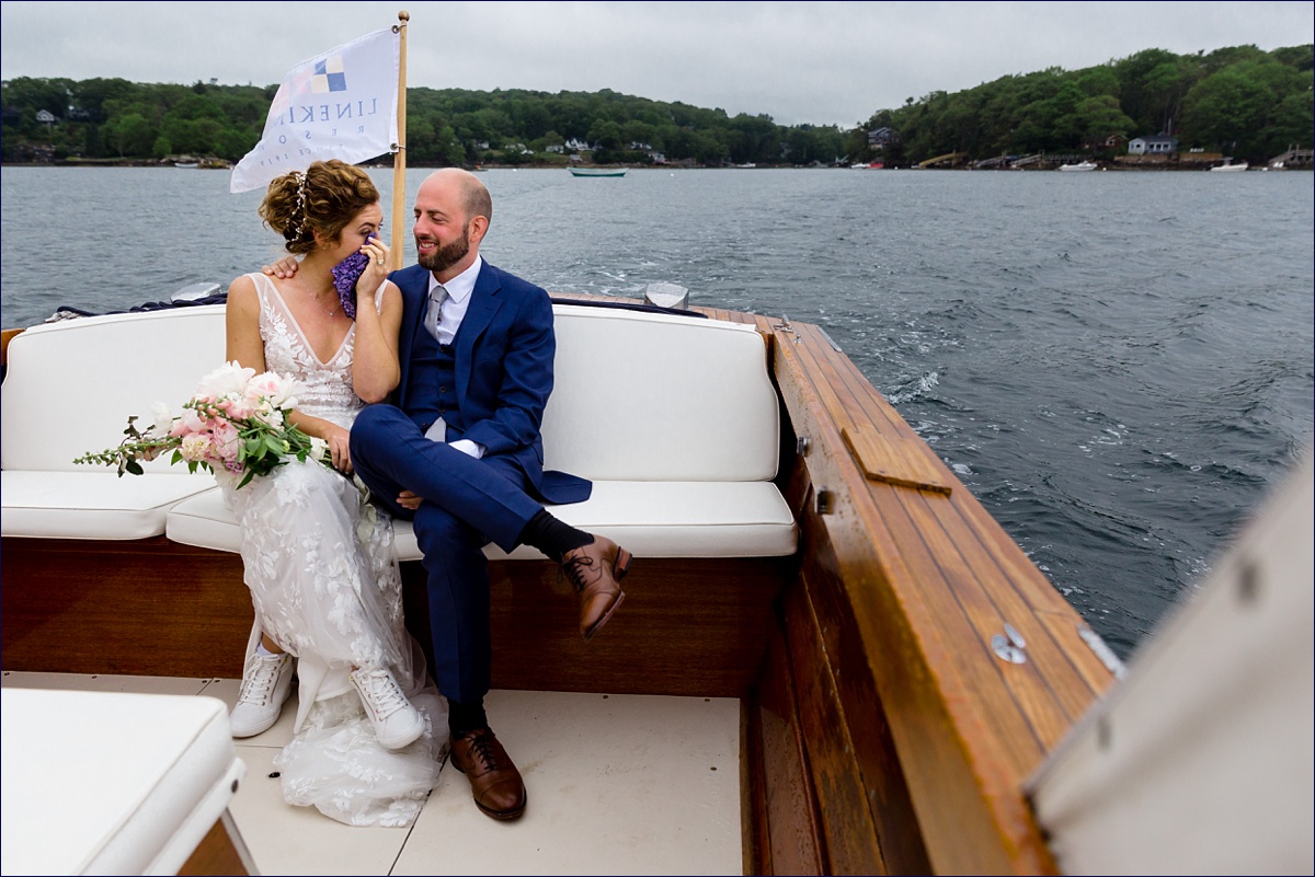 Linekin Bay Resort Wedding Photographer in Boothbay Maine the newlyweds celebrate and wipe away a couple of tears out on a Cris Craft boat out in the ocean 