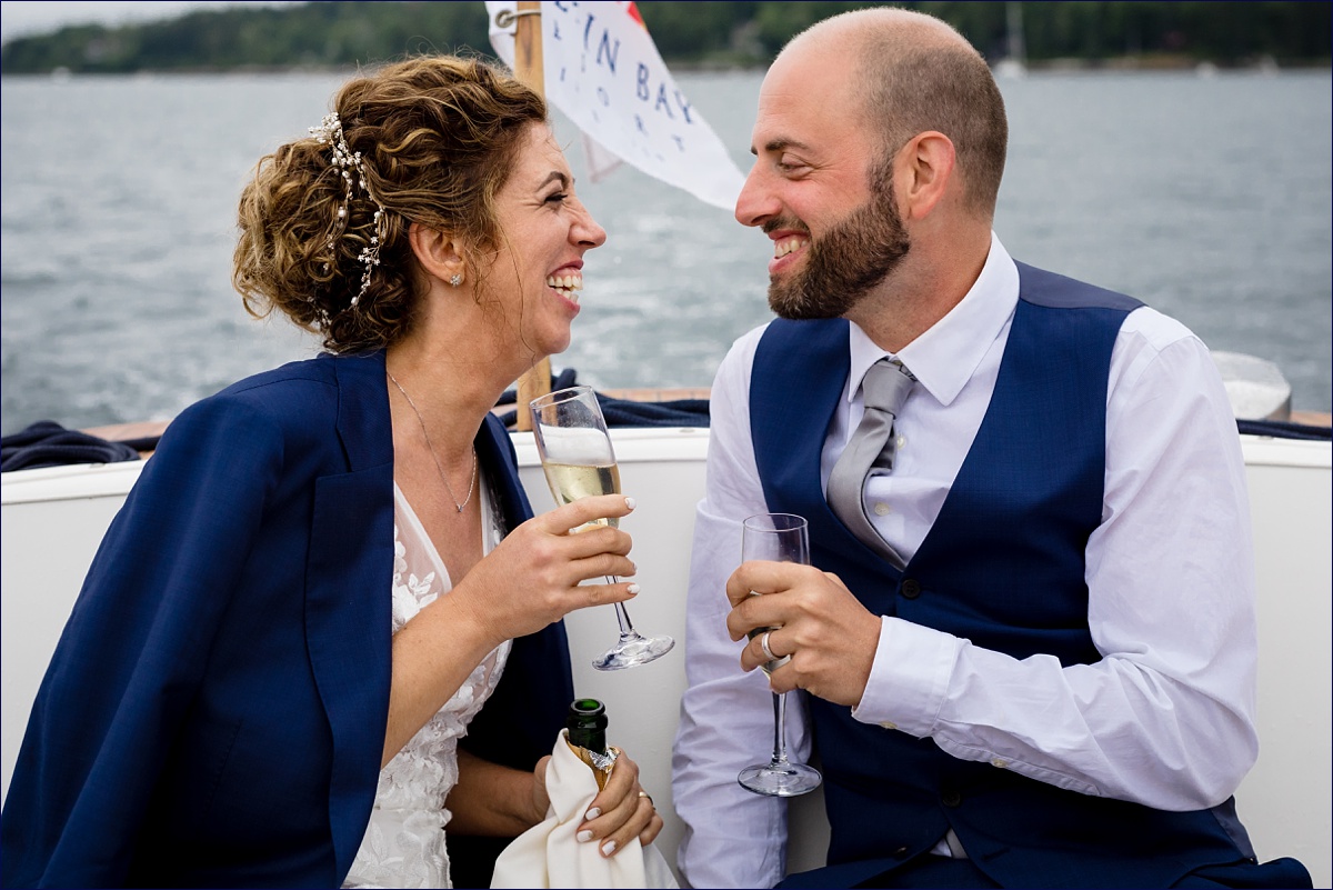 Linekin Bay Resort Wedding Photographer in Boothbay Maine the newlyweds toast with a bottle of champagne out on a Cris Craft boat in the ocean