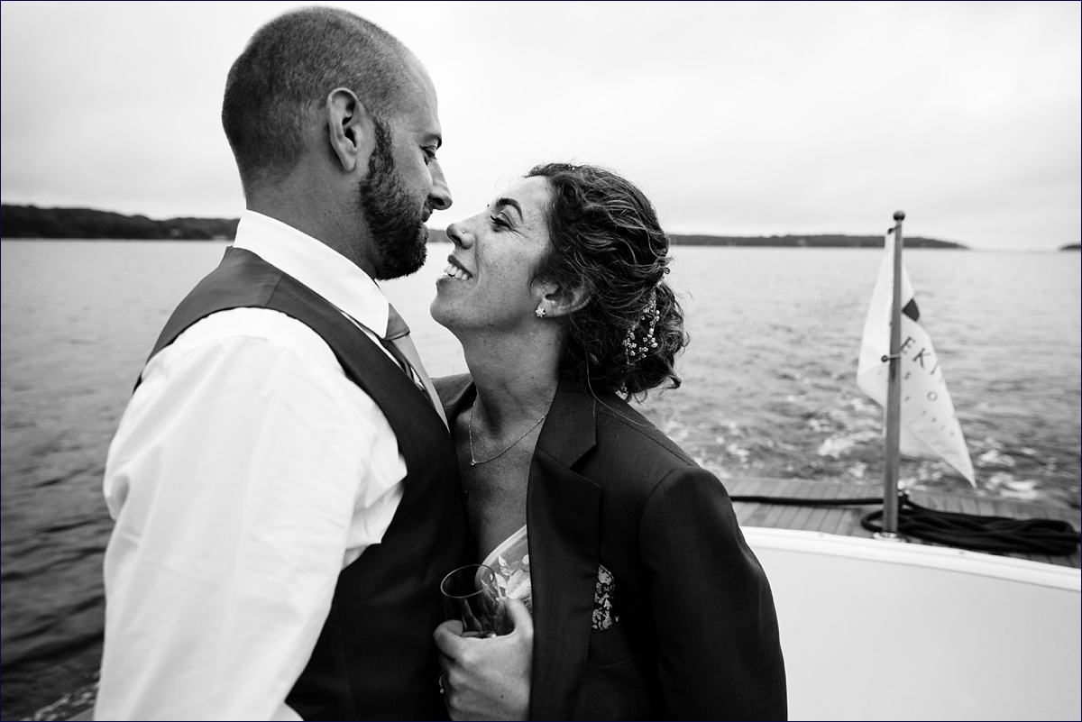 Linekin Bay Resort Wedding Photographer in Boothbay Maine the newlyweds get in close for a kiss on a Cris Craft boat out in the ocean