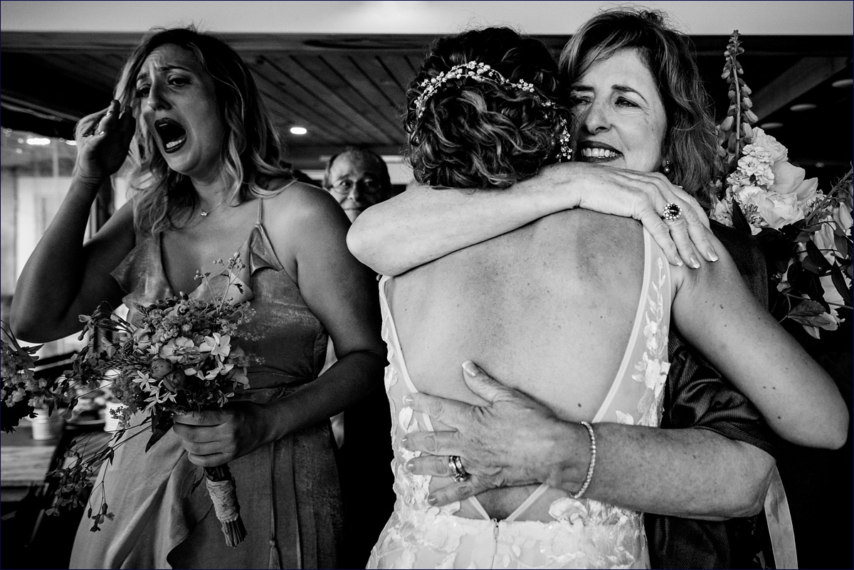 Linekin Bay Resort Wedding Photographer in Boothbay Maine the mother of the groom hugs the bride while a bridesmaid wipes away her tears