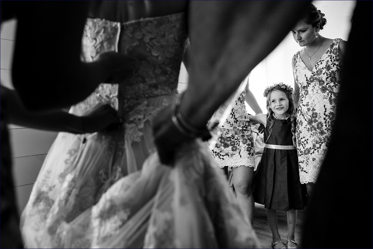 PThe flower girl watches as the bride gets into her wedding gown