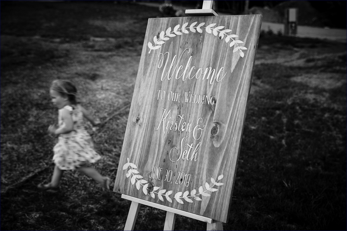 A little one runs in the background of the wooden wedding day sign