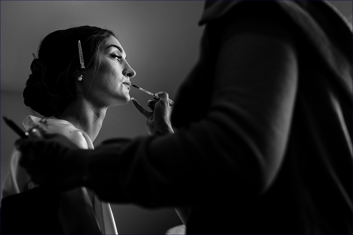 The bride gets her lips touched up during the getting ready for her wedding
