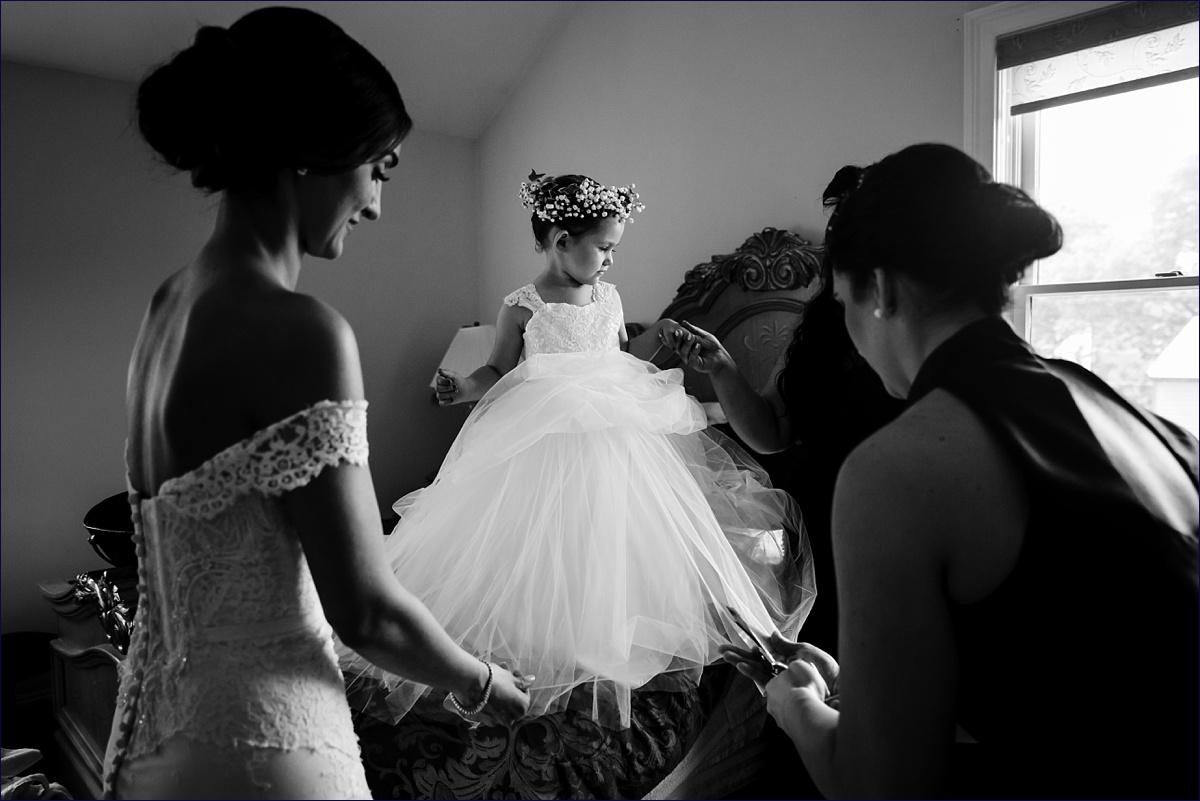 The flower girl gets her dress altered real quick on the wedding day by the Koumbara and the bride