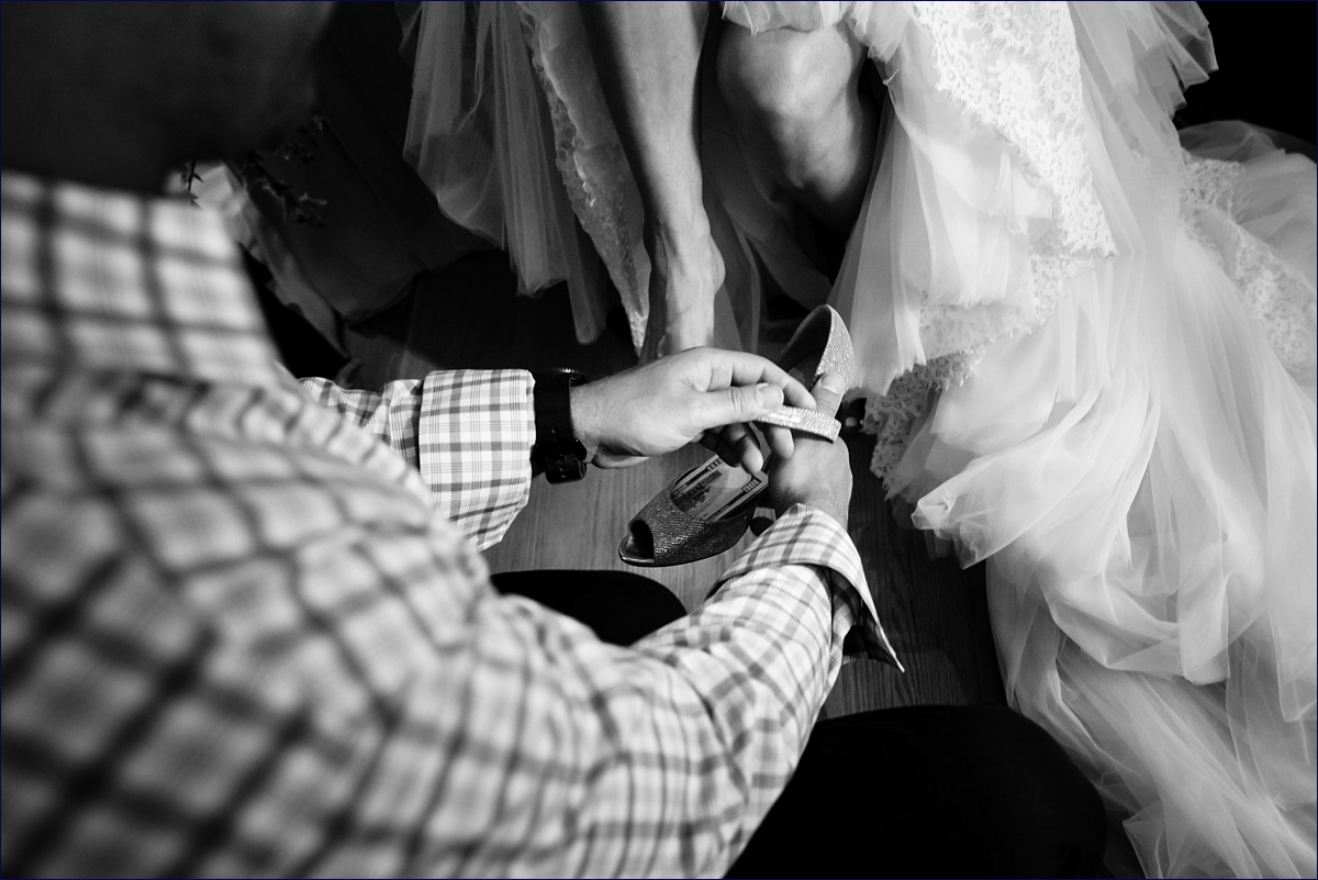 The youngest cousin of the bride puts money in the bride's shoe as part of a Greek tradition and custom on her wedding day