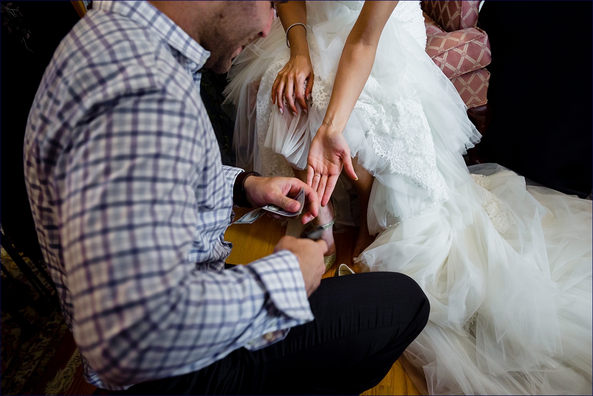 The youngest cousin of the bride puts money in the bride's shoe as part of a Greek tradition and custom on her wedding day
