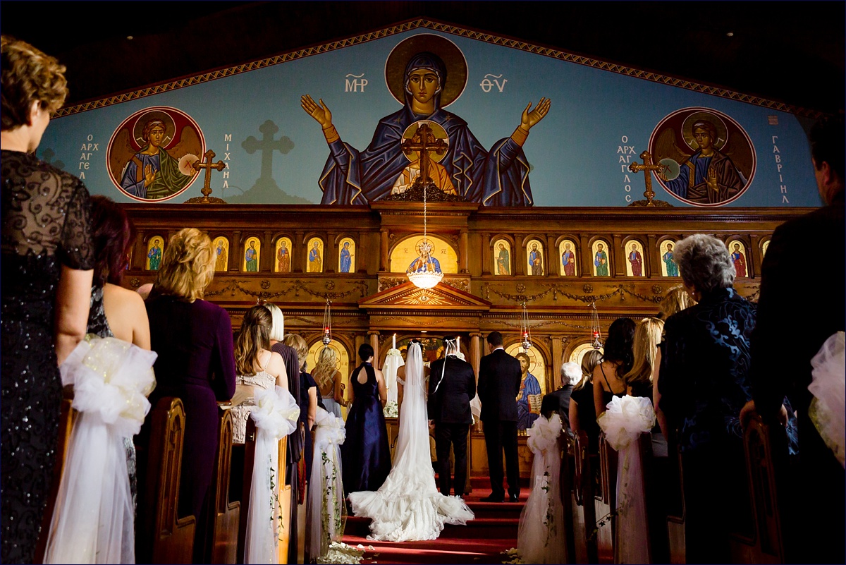 The bride and groom stand on the altar with the Stephana crowns on during the Greek ceremony