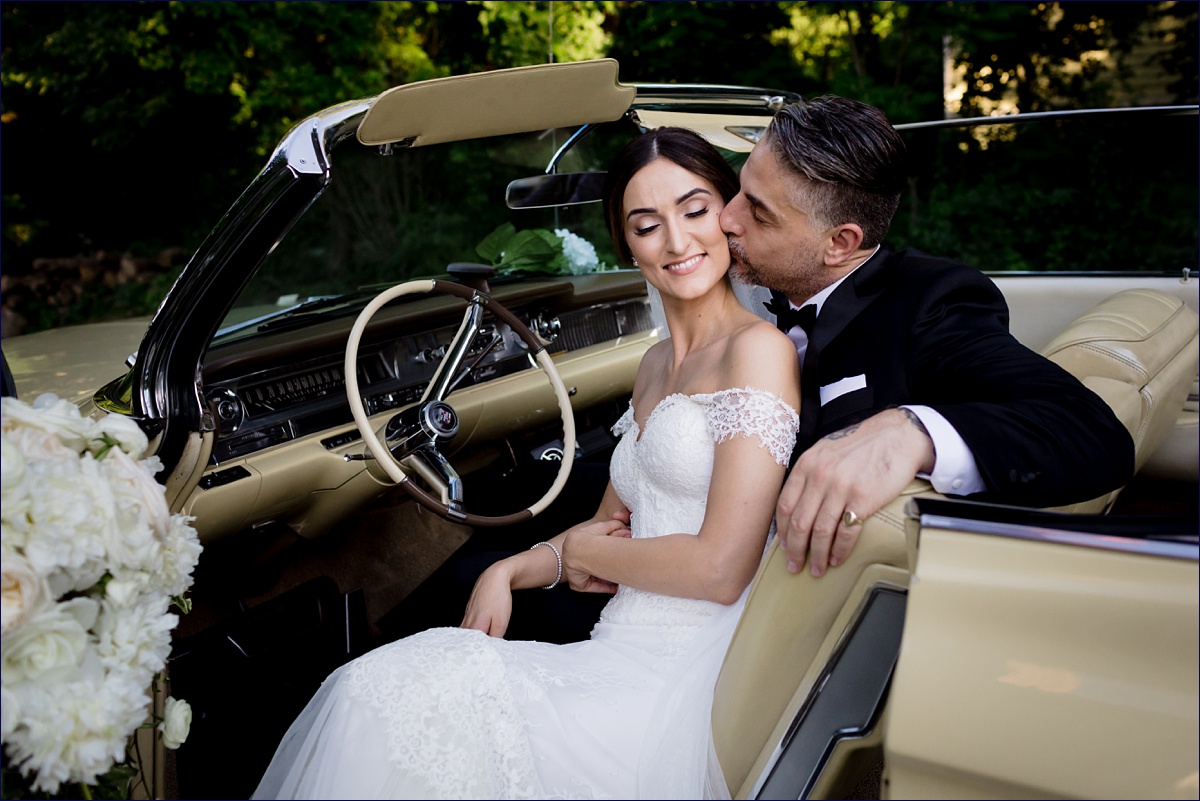 Greek Orthodox Massachusetts Wedding Photographer the bride and groom share a kiss and cuddle in a vintage car