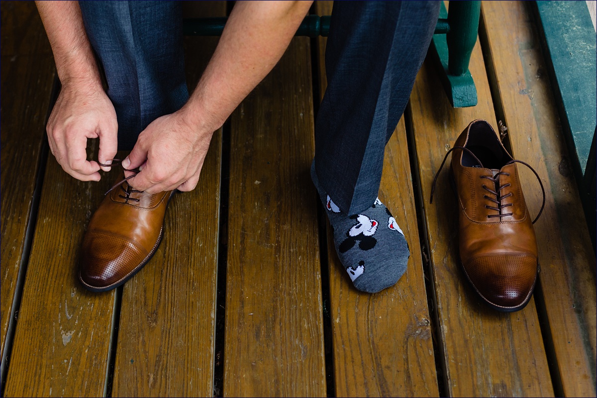 The groom gets ready for the wedding day by putting on his wedding shoes
