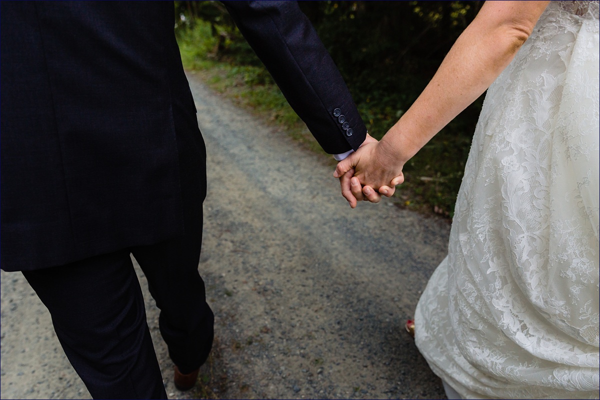 The bride and groom hold hands as they walk to the Ellsworth Maine ceremony