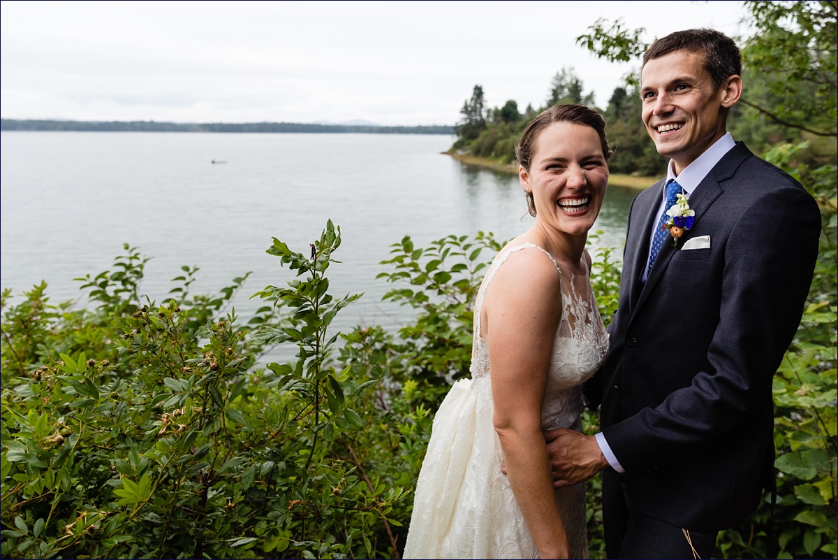 Trenton Maine Wedding Acadia Bar Harbor the bride and groom laugh together on the water overlooking Mt Cadillac