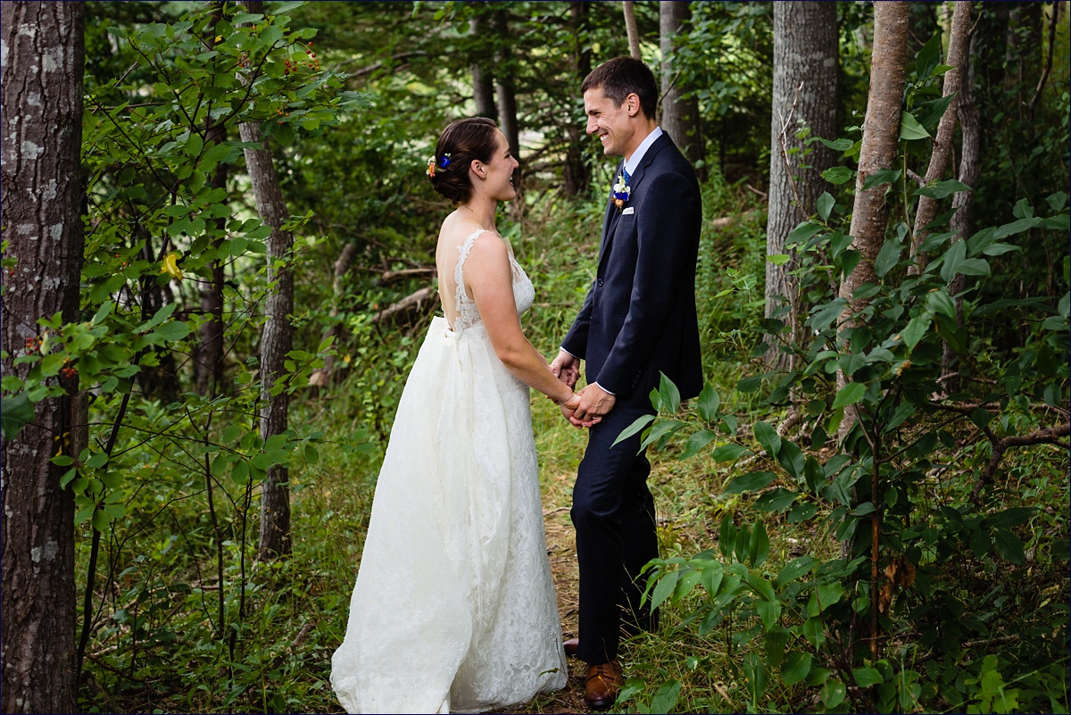 The bride and groom hold hands in the forest in Ellsworth Maine