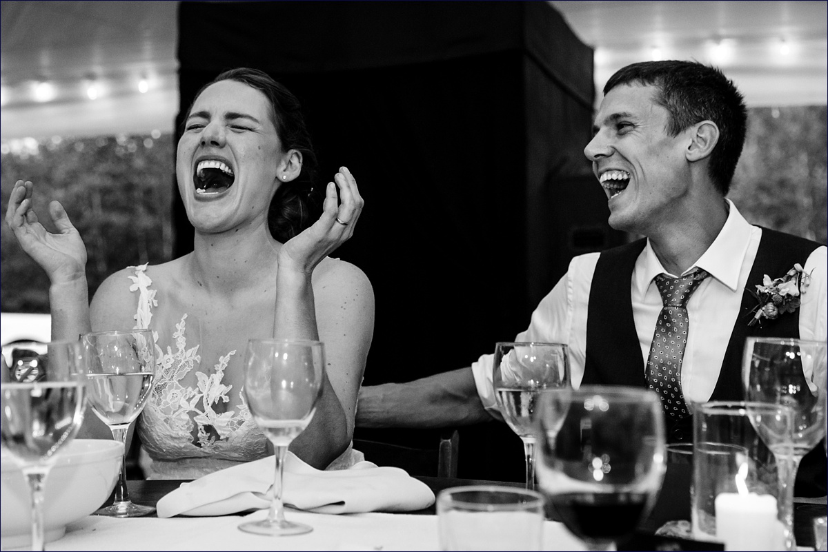 Trenton Maine Wedding outdoors with the newlyweds laugh at a speech during their reception