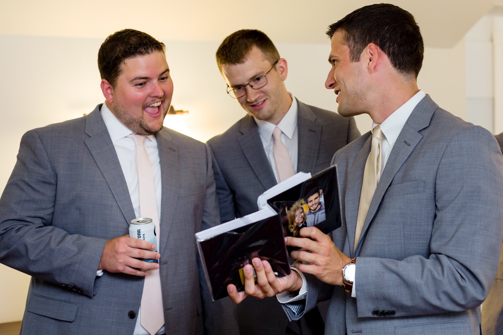The groom and the groomsmen look at a photo book the bride created for her groom on their wedding day