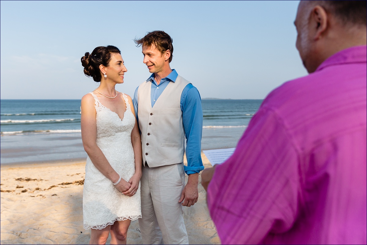 The bride and groom during their elopement ceremony on the beach during summer golden hour
