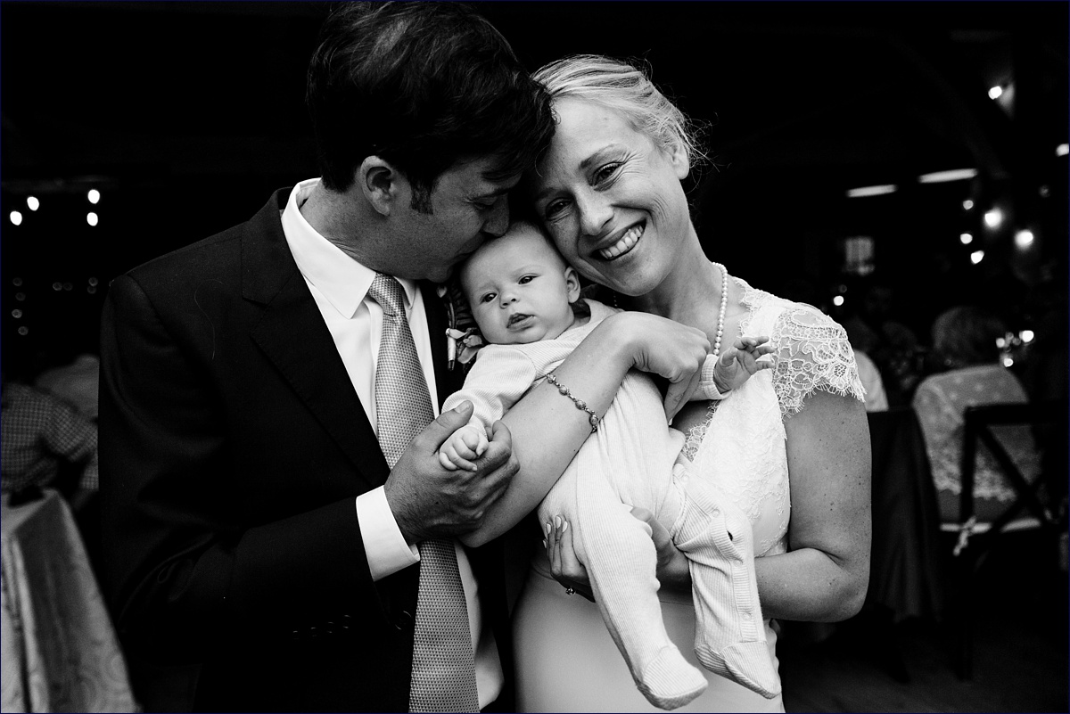 Bride and groom kiss their daughter at their wedding reception at Primo Restaurant