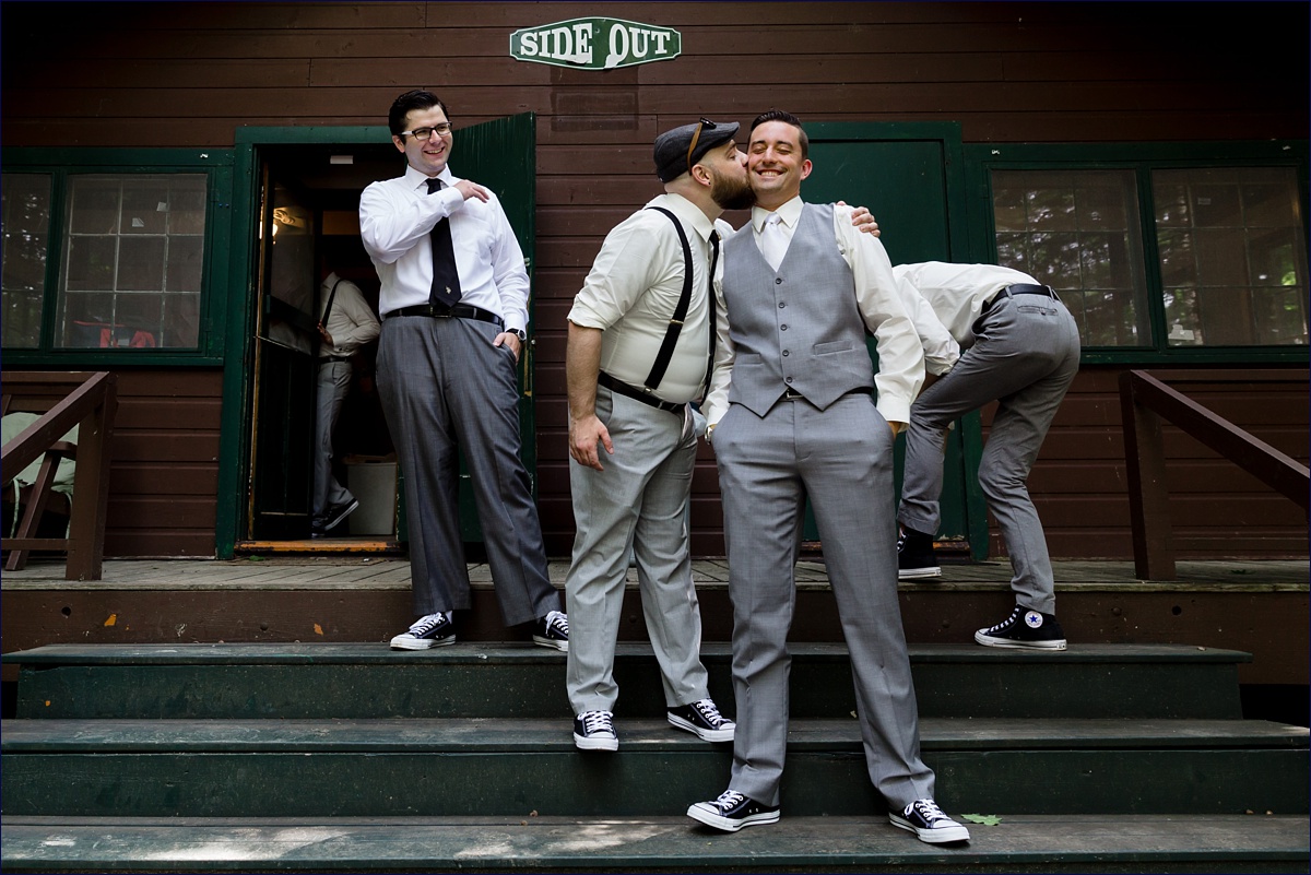 One of the groom's friends gives him a wedding day kiss on the cheek