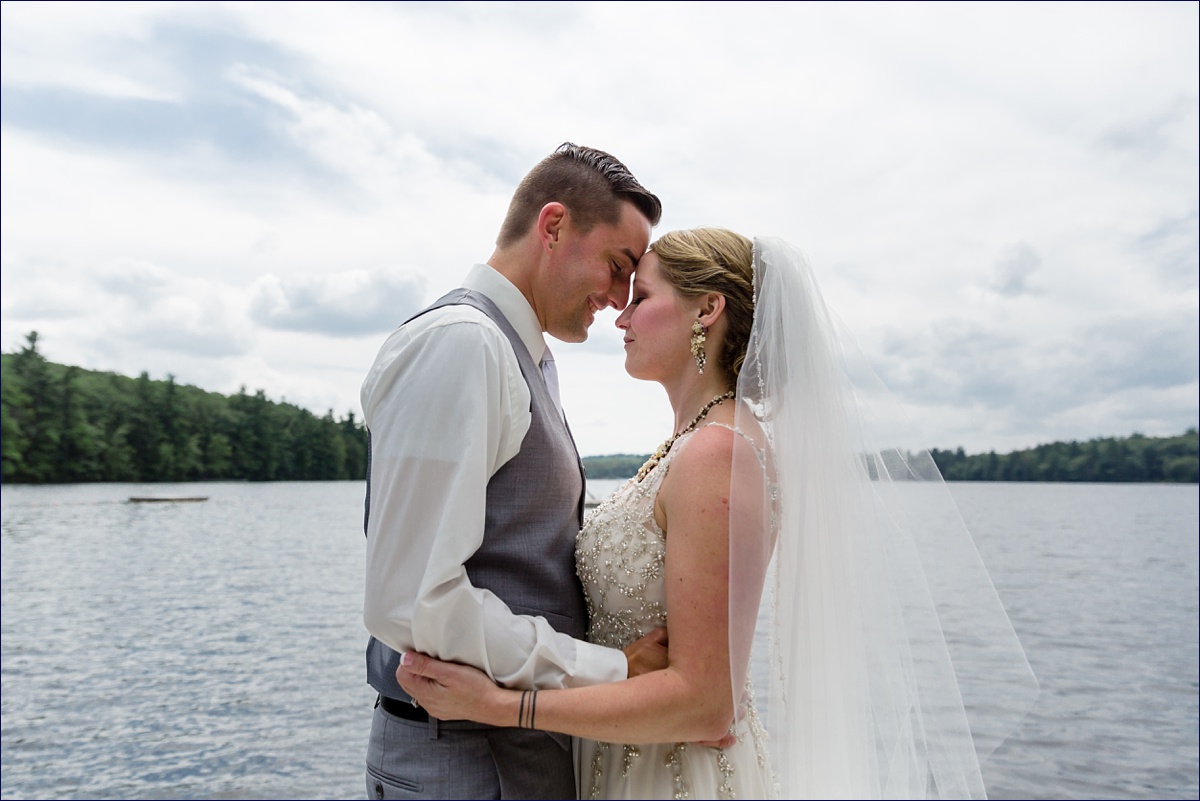 The bride and groom touch foreheads together out on the water