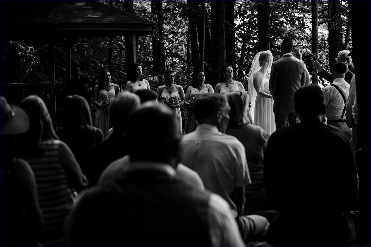 The bride bows her head in front of her loved ones during the wooded camp ceremony in New Hampshire