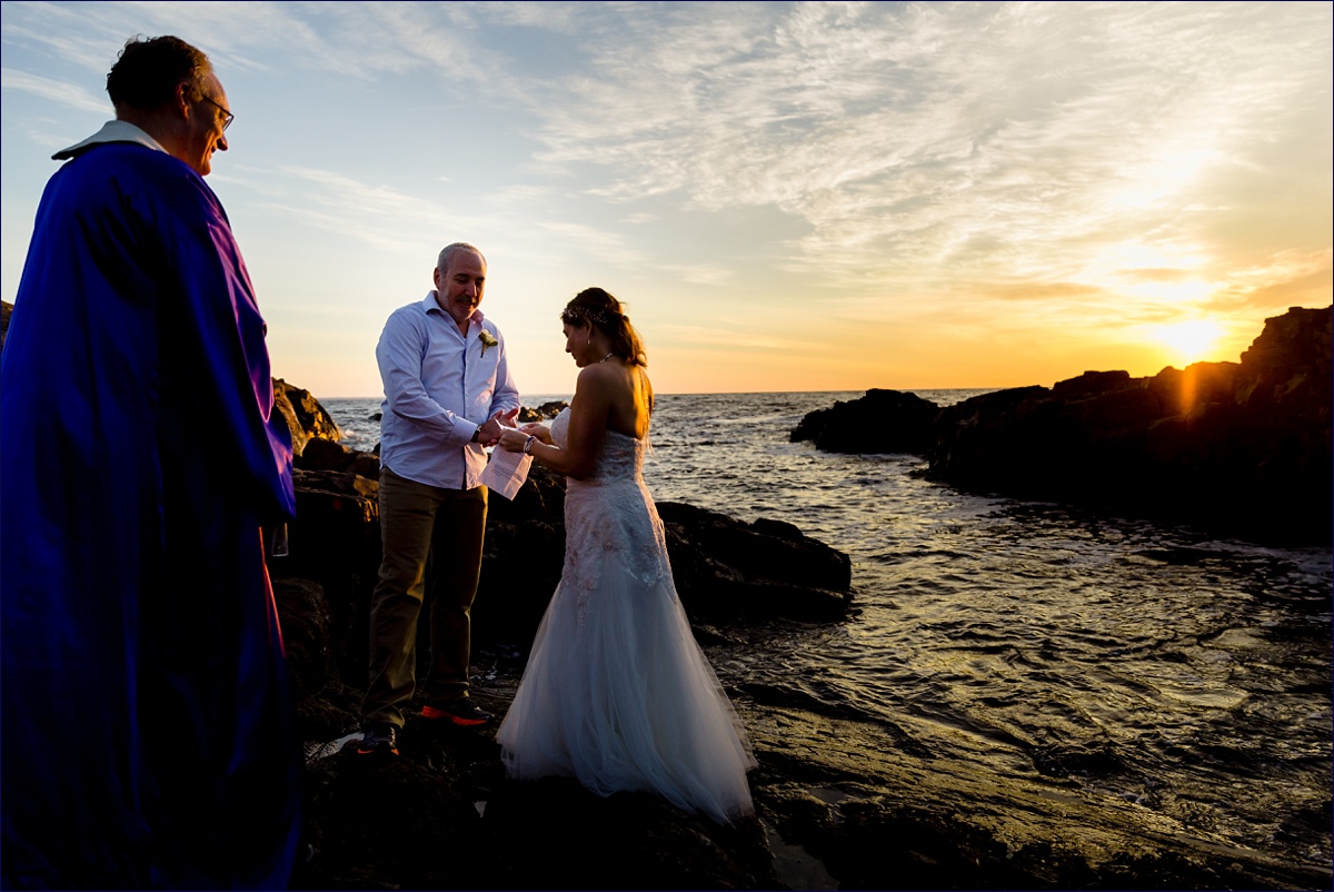 Bride and groom read their vows at their sunrise elopement on the rocks in Ogunquit Maine