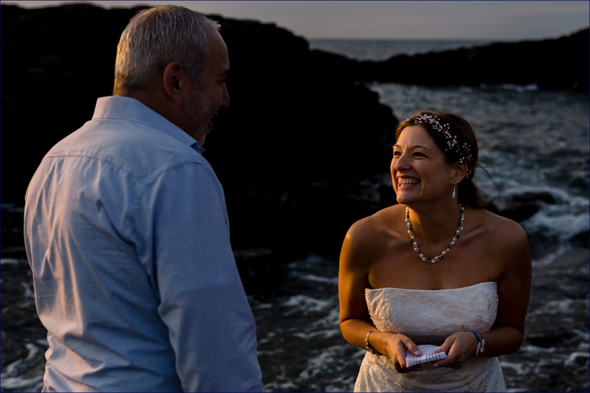 Maine elopement at sunrise with the bride laughing as she says her vows to her groom on the rocks of sunrise on Marginal Way
