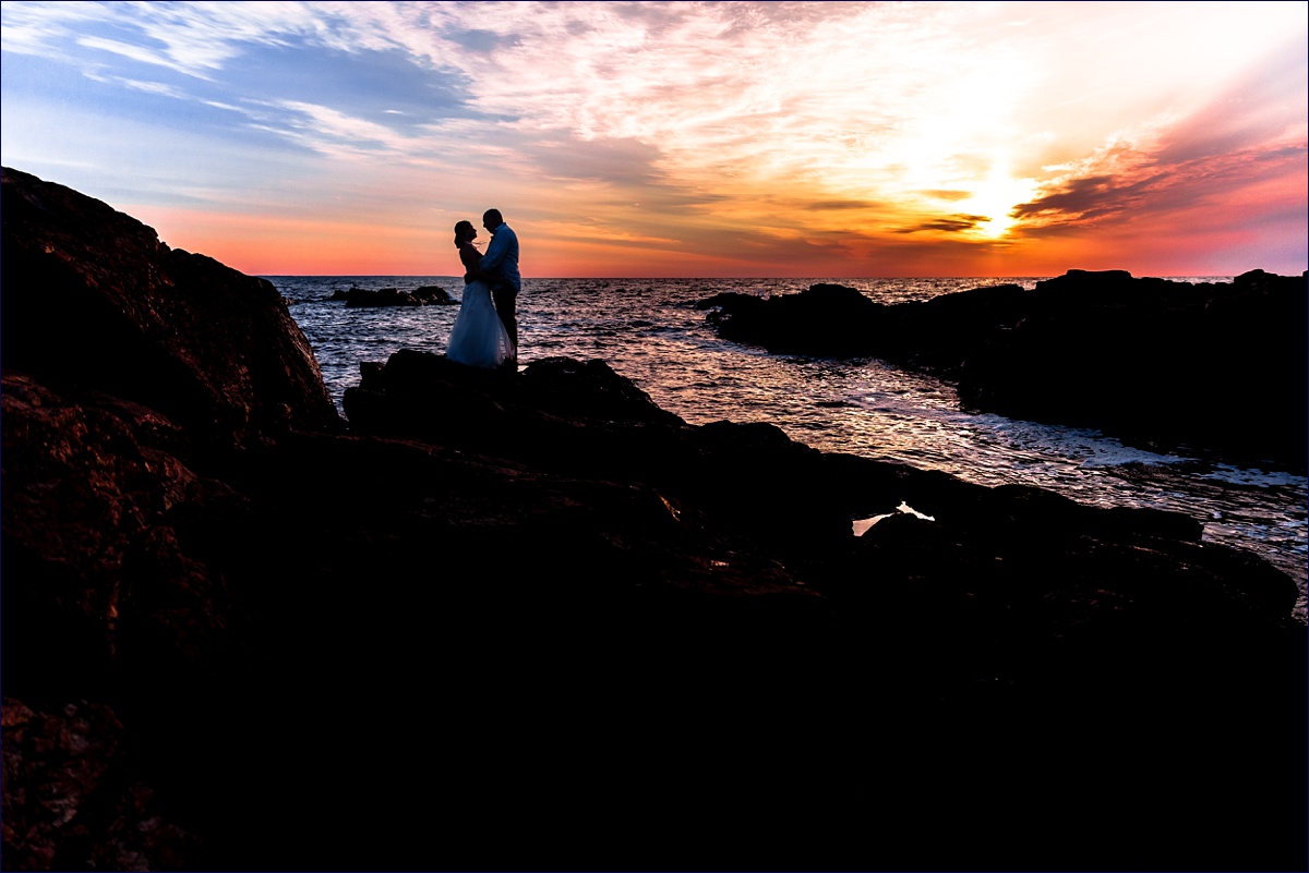 Bride and groom hug each other close as the sun rises on their Ogunquit Maine elopement on the rocks on Marginal Way