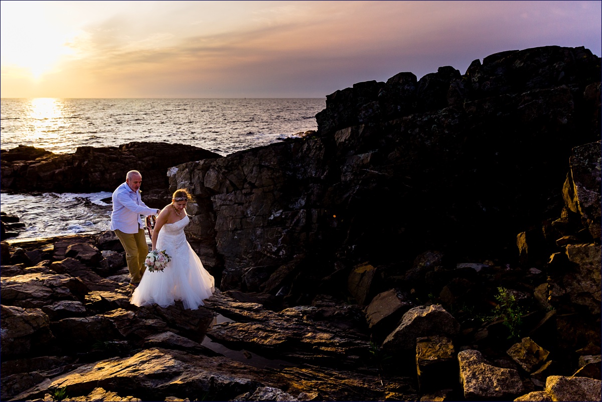 Bride and groom climb the rocks at sunrise in Ogunquit Maine