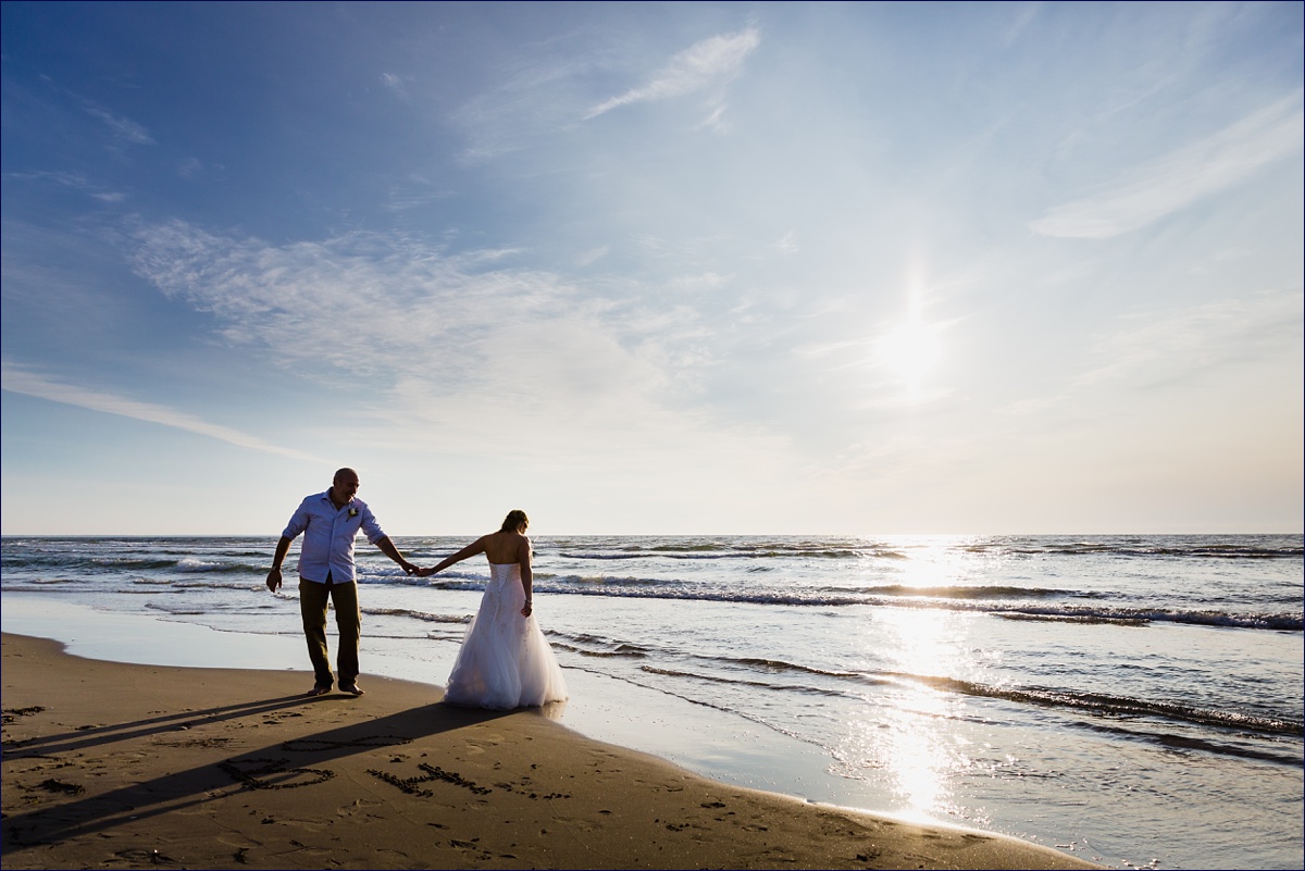 Bride and groom walk out to the edge of the ocean on their Maine elopement morning
