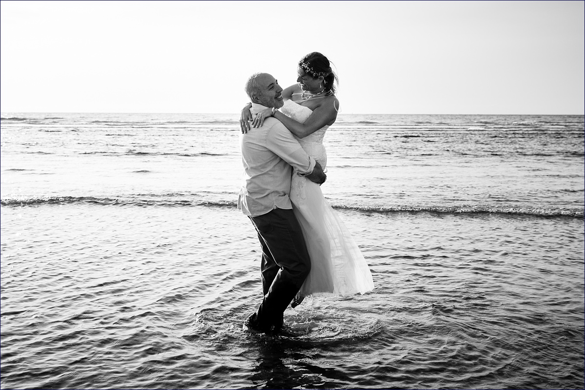Groom grabs the bride in a hug out in the ocean