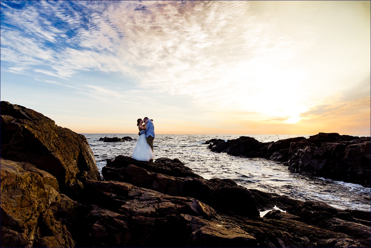 Maine elopement where the bride and groom hug each other close as the sun rises in Ogunquit on the rocks of Marginal Way