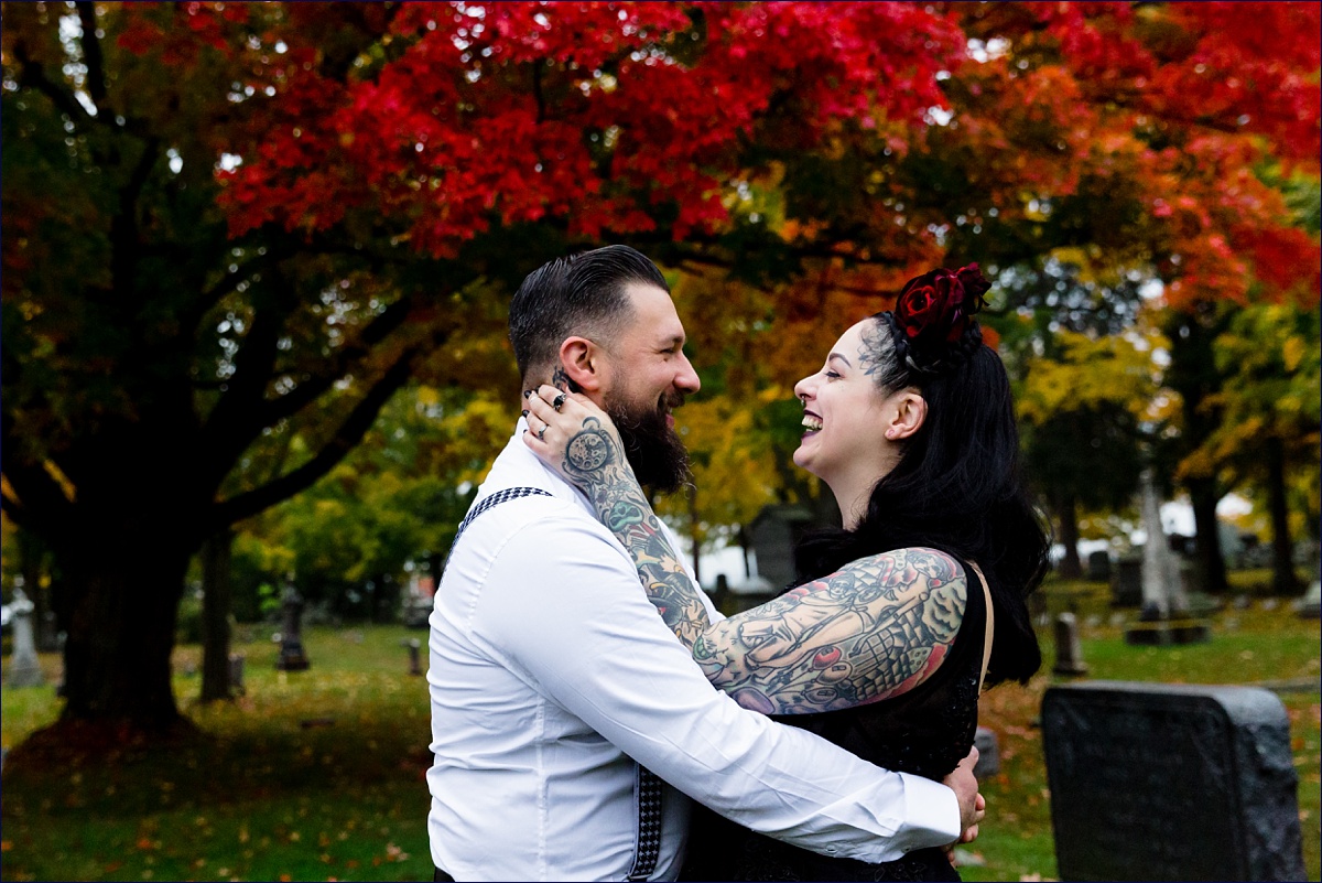 Dover New Hampshire elopement with the bride and groom laughing with one other close with the backdrop of a bright red fall tree on their wedding day