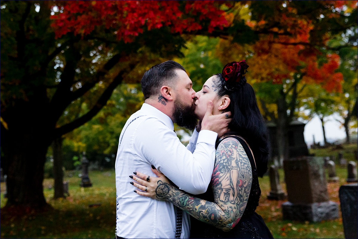 The bride and groom kiss each other close with the backdrop of a bright red fall tree on their wedding day in Dover NH