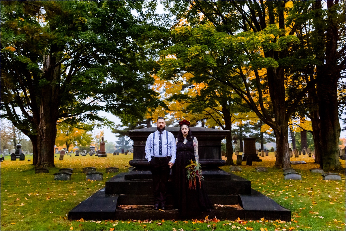 The stoic bride and groom stand at a gravesite at their Dover New Hampshire elopement