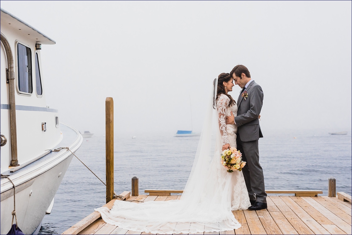The bride and groom cuddle close in front of the foggy ocean in Boothbay Maine
