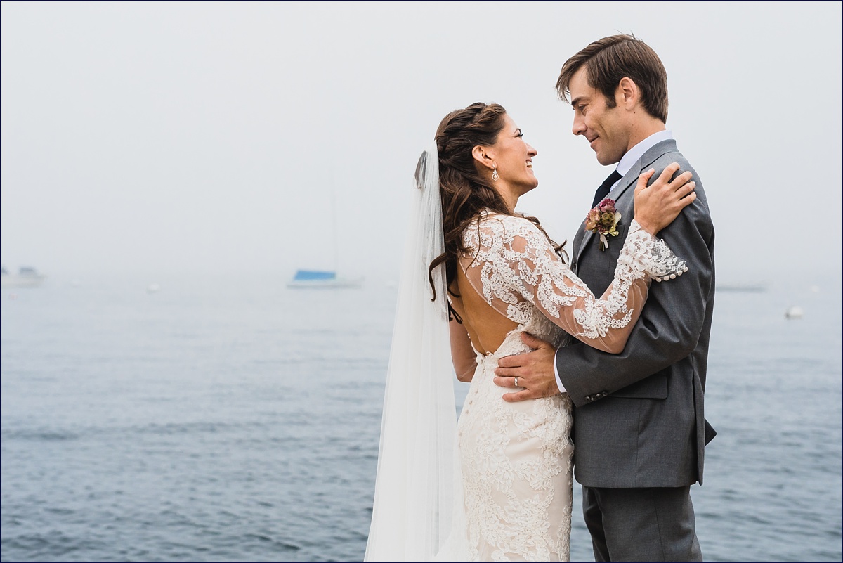The bride and groom cuddle close in front of the foggy ocean in Southport Maine