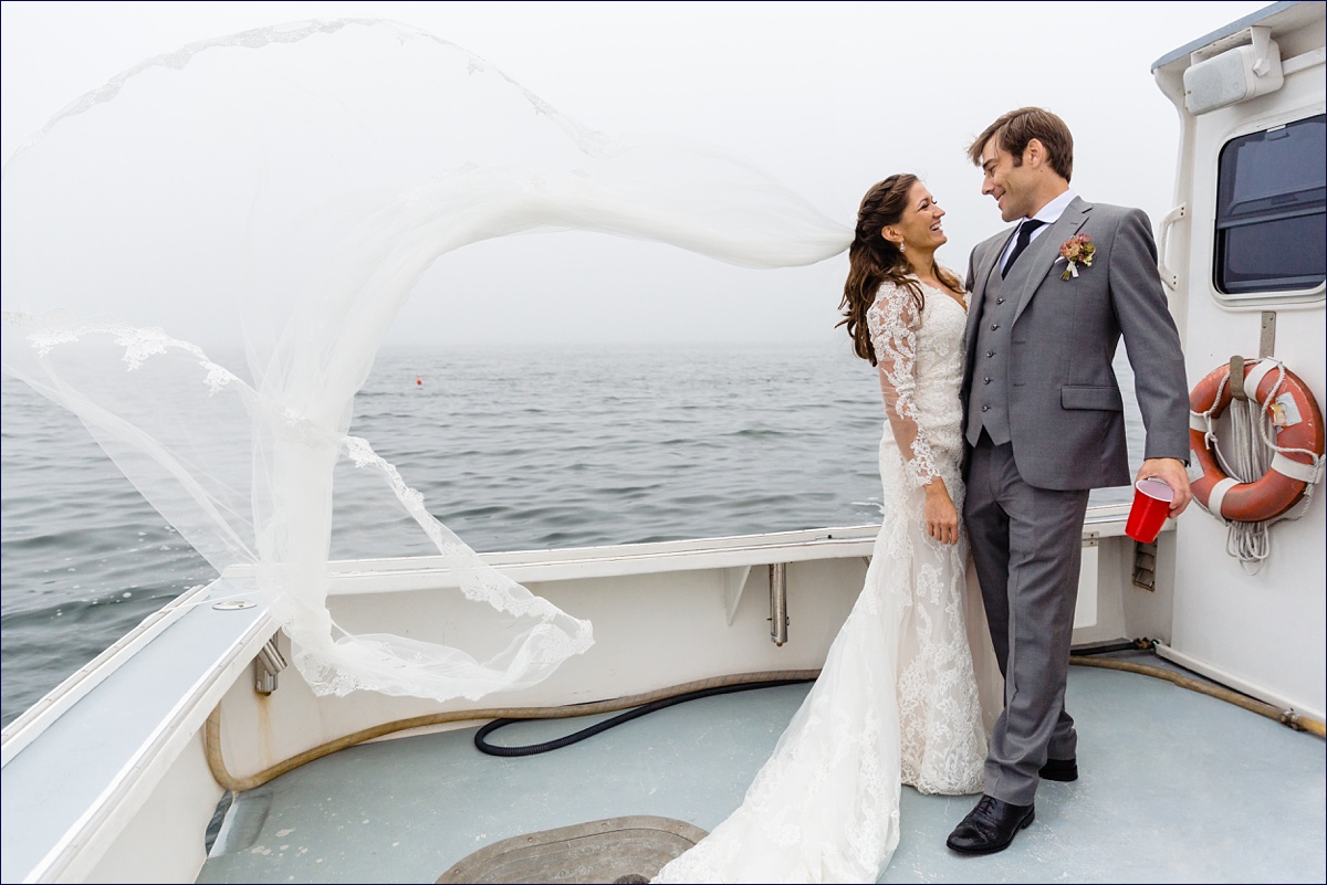 The bride's veil takes off in the wind as she and her husband ride the boat to their Linekin Bay Resort wedding reception