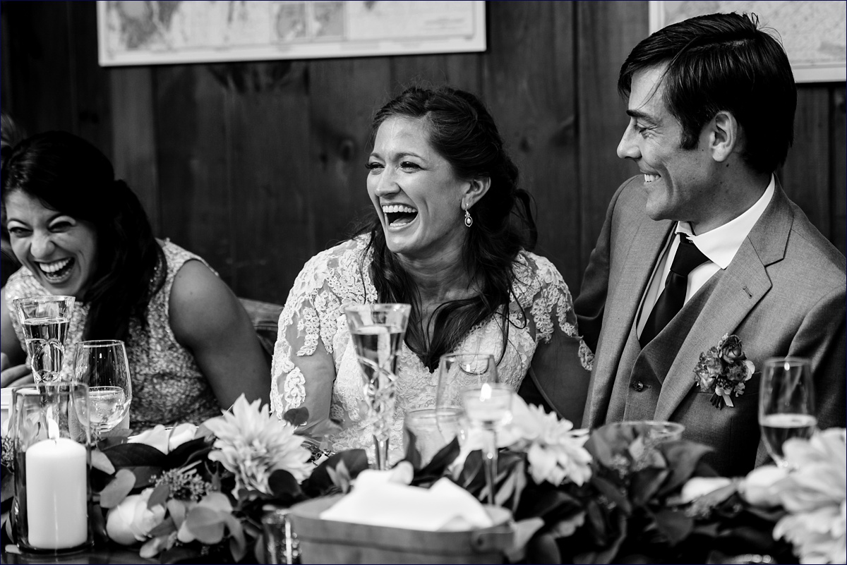 The bride and her maid of honor laugh at her father's speech at the reception