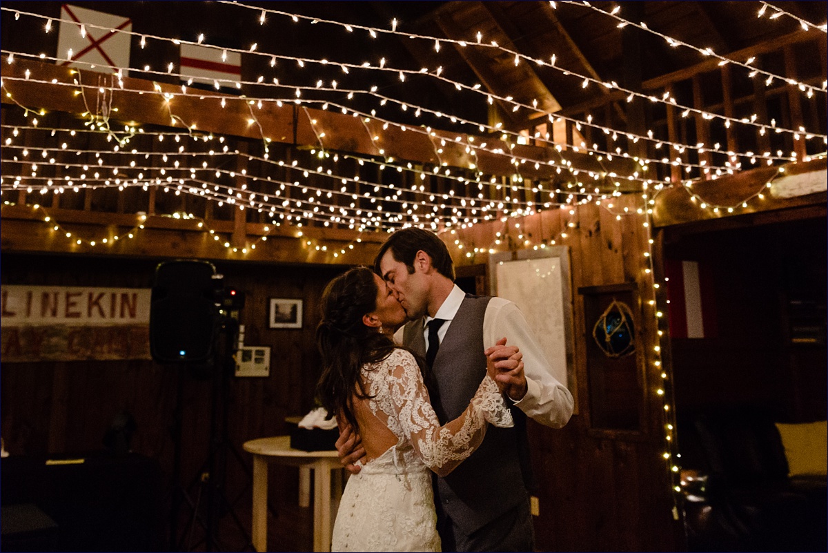 The bride and groom kiss on the dance floor at their reception under the twinkle lights