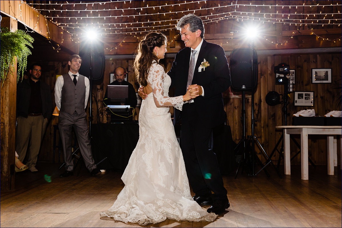 The bride and her father dance at the Maine wedding reception while the groom lovingly watches