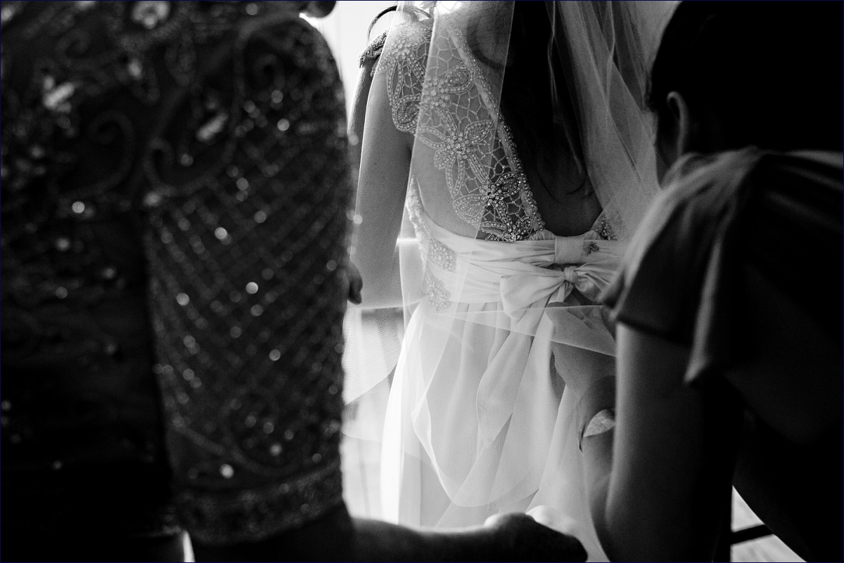 The bride gets into her wedding gown with a little help from her stepmom and her sister
