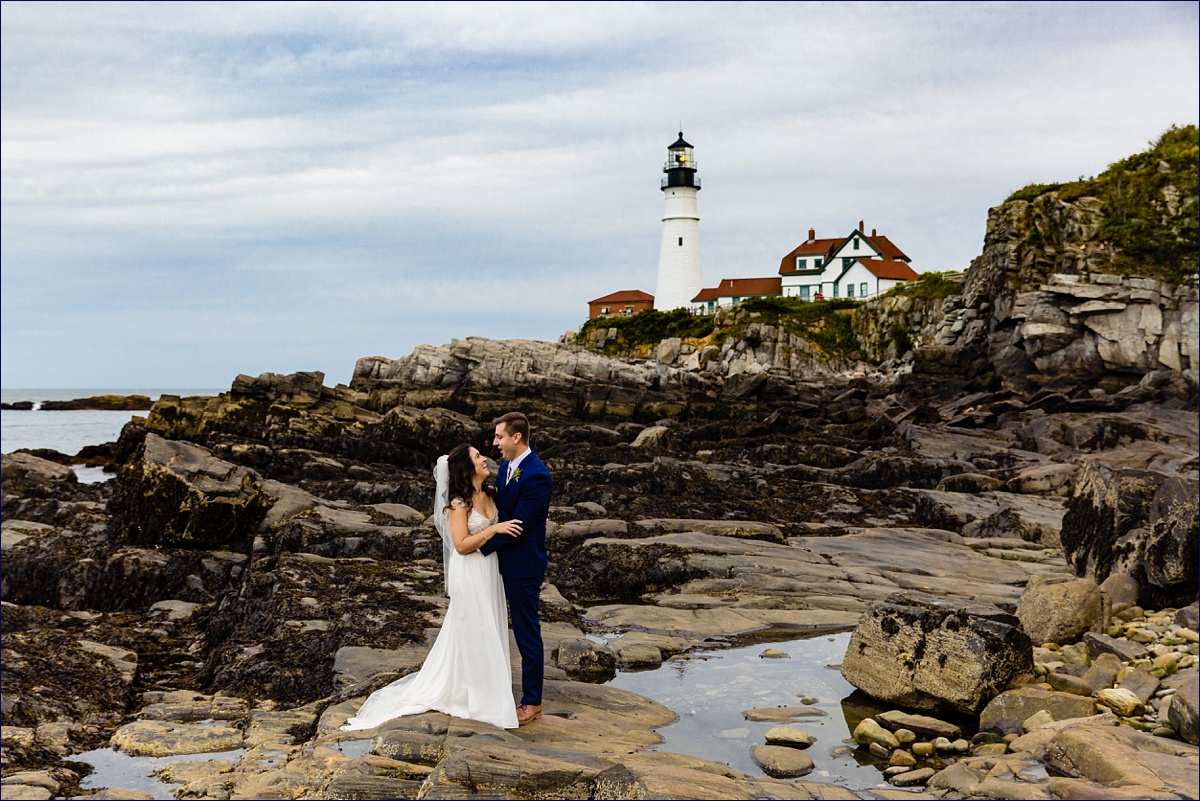 Portland Headlight wedding in Maine and the newlyweds stand out on the rocks with the Lighthouse behind them on their wedding day