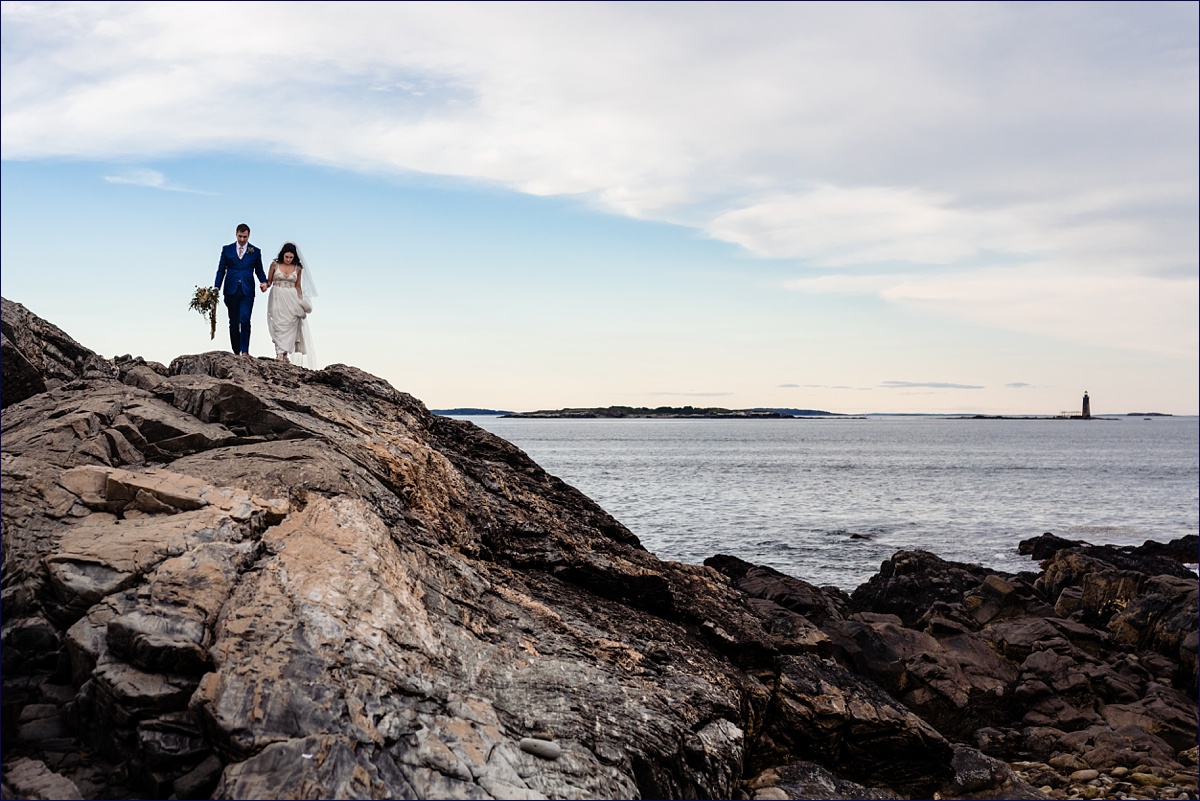 Cape Elizabeth elopement with the bride and groom holding hands and walk on the rocky cliffs after they are married