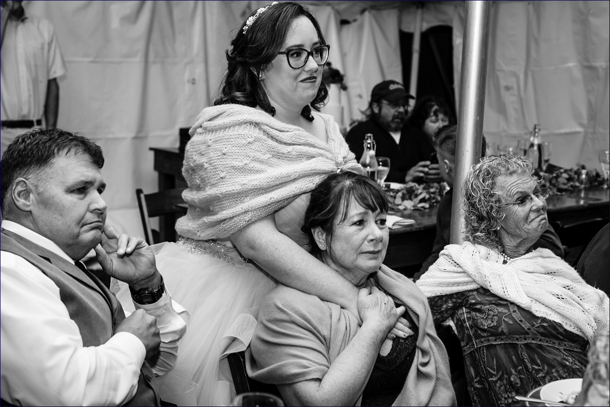 The bride holds onto her mom while her new husband dances with his mom