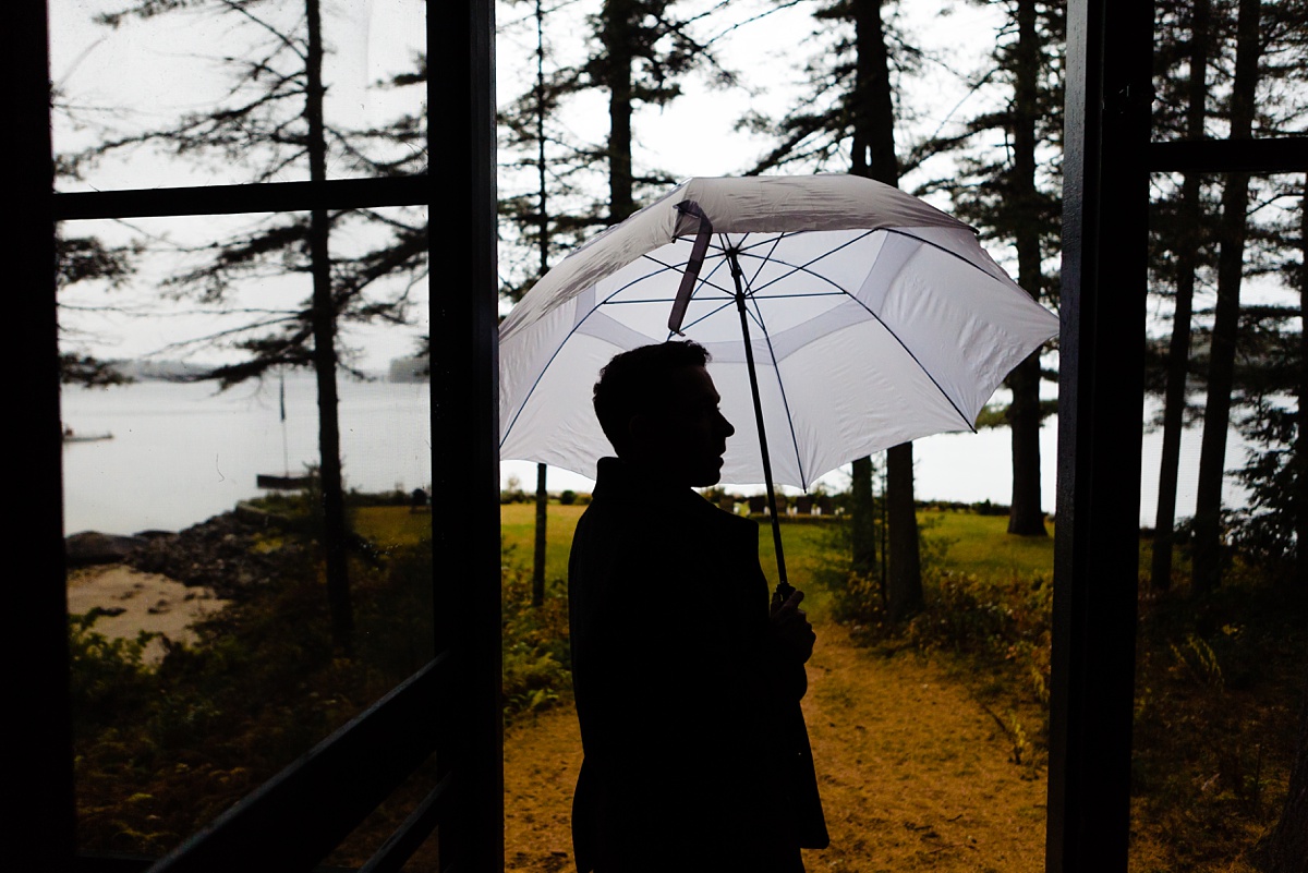 The groom heads to the first look under an umbrella at Migis Lodge