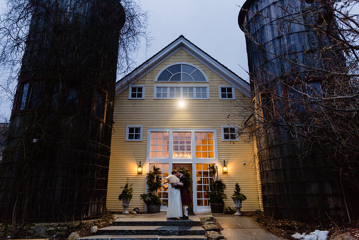 The bride and groom stand by the silos at the Bedford Village Inn