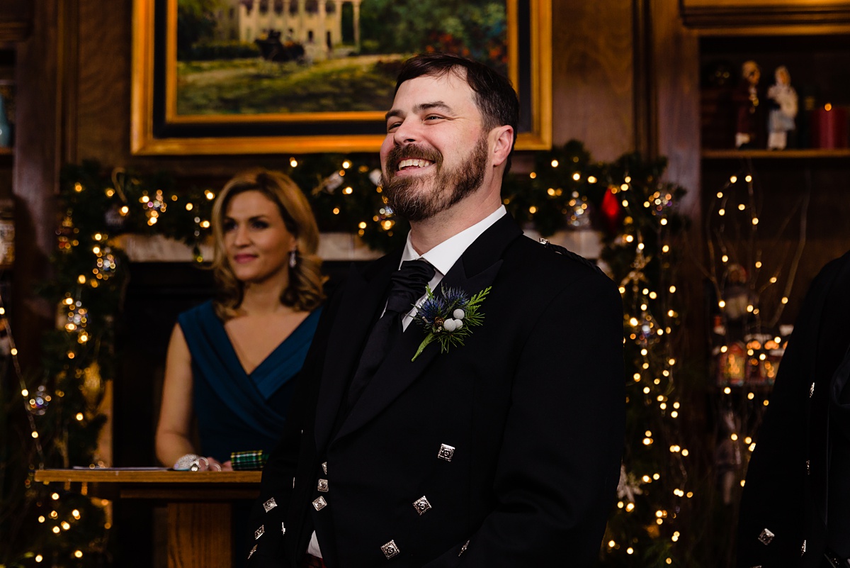 The groom smiles as his bride enters the ceremony in the Overlook Room decorated for the holidays in Bedford NH