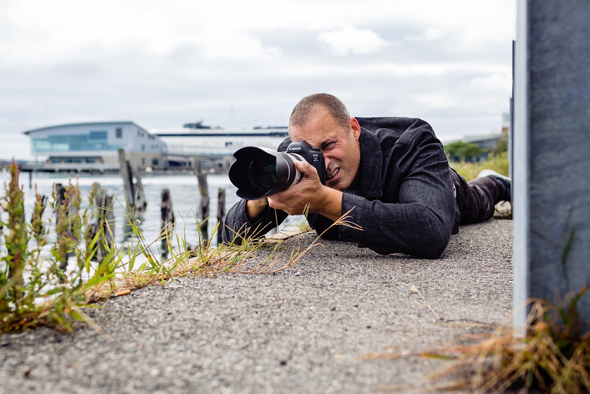 Nigel Barker from America's Next Top Model gets low on the ground to photograph for his students how he does fashion photography in Portland Maine