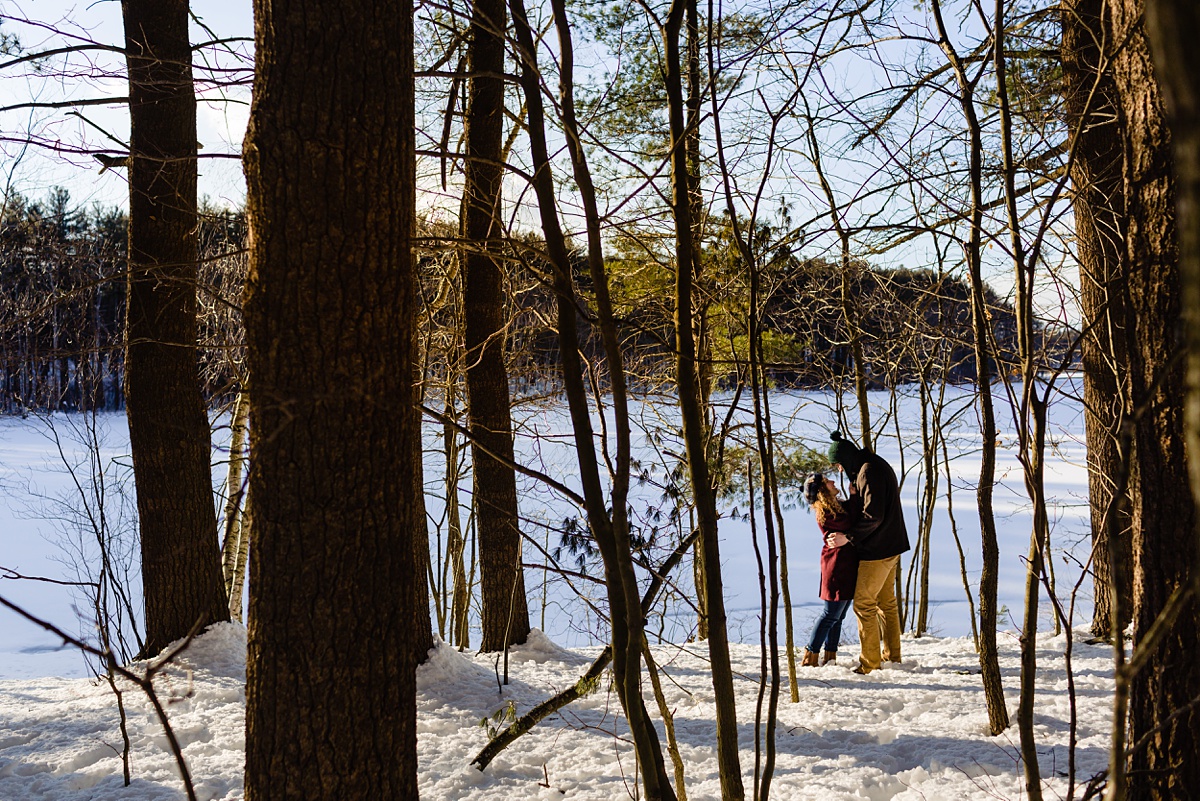 Engagement Session at snowy Fells Reservation in the winter where the couple stands near the water in the woods