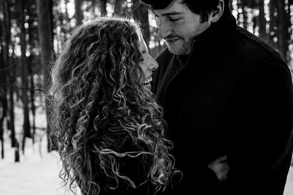 Engagement Session in winter with the smiling couple deep in the snow and woods at Fells Reservation with their Maine Wedding Photographer
